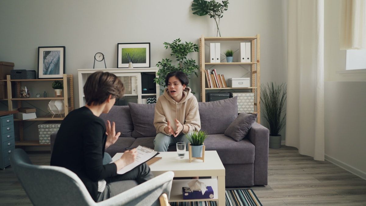 Two people in conversation on a sofa in a bright room